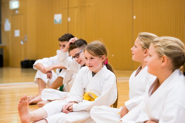 LSB NRW Fünf Kinder in weißen Anzügen sitzen in einer Trainingshalle.